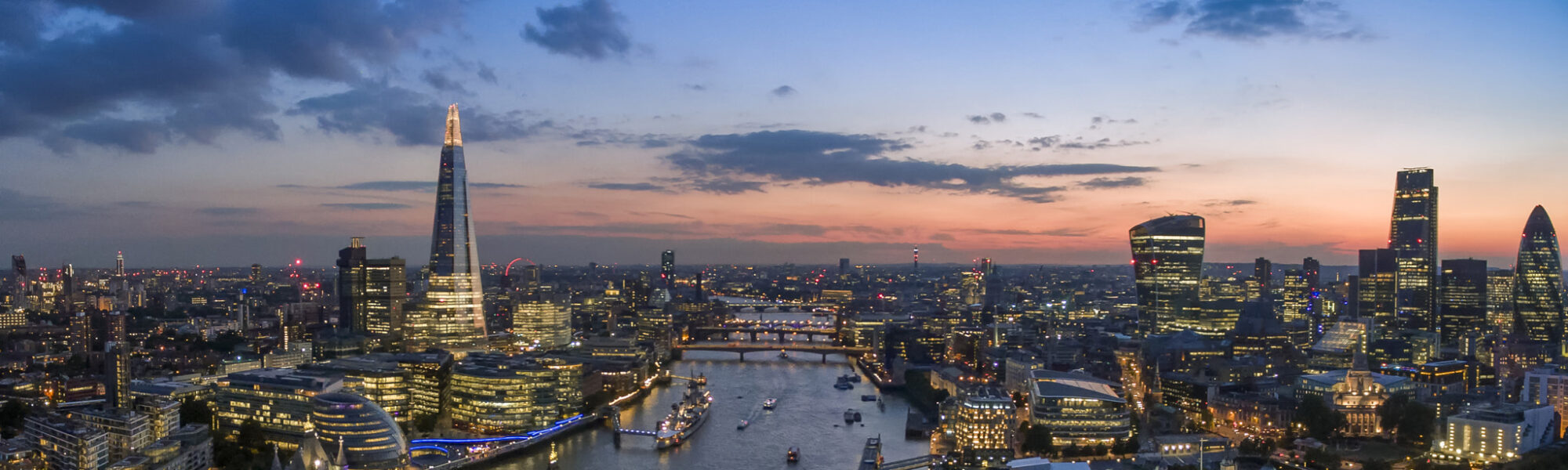 The London skyline at sunrise, showing key London landmarks such as the Shard, Tower Bridge, Tower of London.