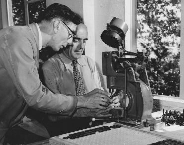 An old photo of two men at work using a machine
