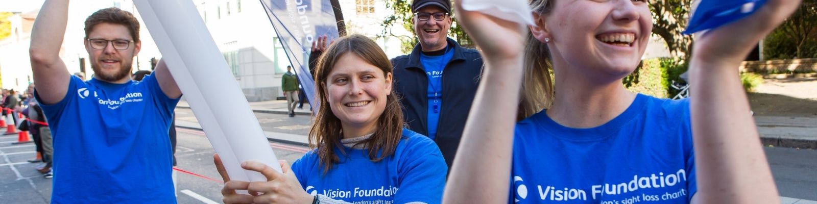 Four people cheering with blue Vision Foundation t-shirts