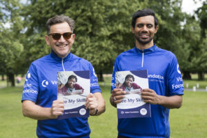 two men in blue vision foundation cycling jerseys pose holding copies of the Vision Foundation See My Skills report