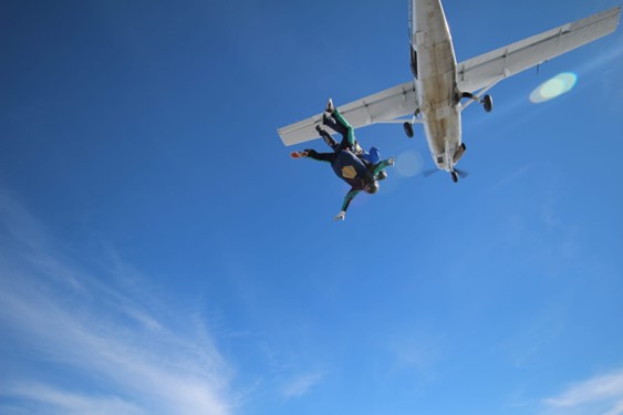 Picture showing two people jumping out of an aeroplane together, strapped to one another.