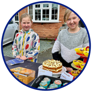 Two young girls selling baked goods at a stall for Vision Foundation (Little Big Helpers)