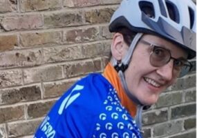 Elizabeth pictured in her helmet and Team Vision cycling jersey looking at the camera smiling