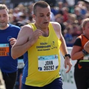 John mid-run. He is wearing a yellow running vest.