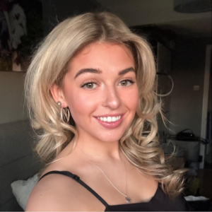 A young woman smiling with blonde wavy hair. This is Zoe